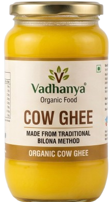 A jar of Vadhanya Organic Food Cow Ghee, showing the yellow ghee inside a clear glass jar with a gold metal lid and a white label.